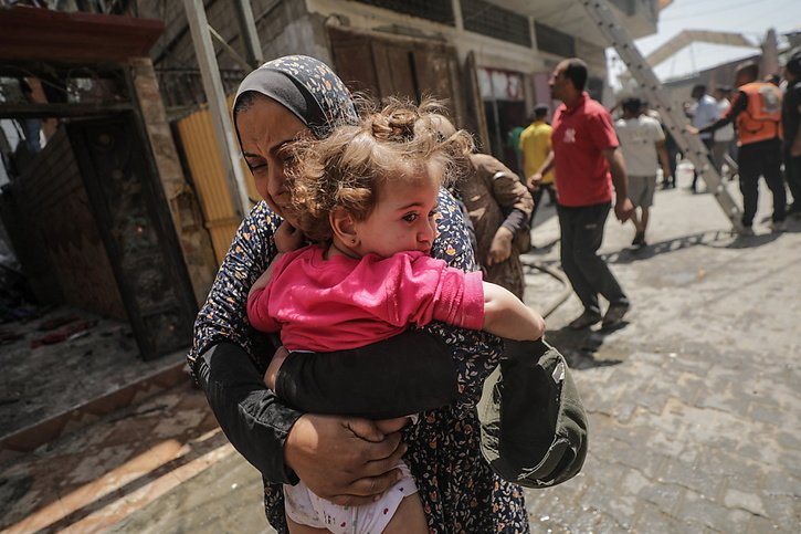 Une Palestinienne portant un enfant fuit après de nouveaux bombardements d'Israël sur le camp de réfugiés d'Al Nuseirat, dans le centre de la bande de Gaza. © KEYSTONE/EPA/MOHAMMED SABER